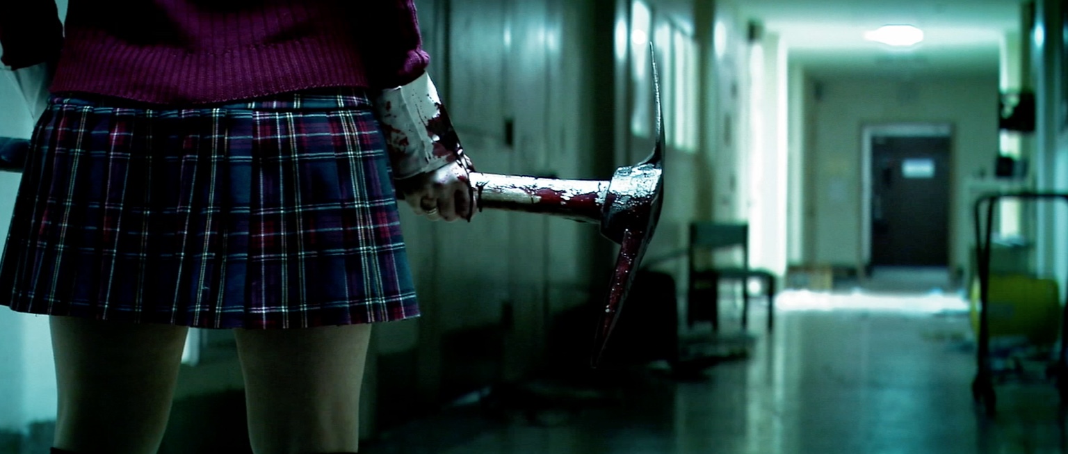 A bloodied pickaxe is held in an empty institutional hallway