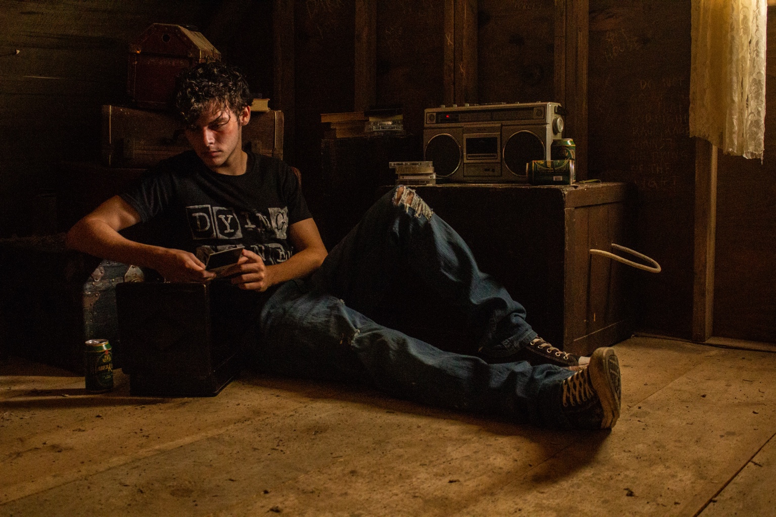 A young man sits inside the dimly lit shed